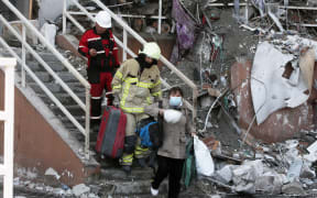 Rescue workers escort a local resident as she leaves a residential building which was hit by a missile strike in Odesa, Ukraine 24 April, 2022.