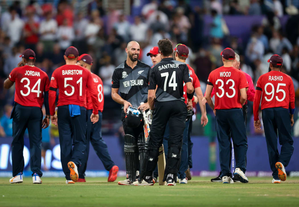 Daryl Mitchell (C) and team mate Mitchell Santner of the New Zealand BlackCaps celebrate as players from England walk off the ground after the ICC Men's T20 World Cup semifinal between New Zealand and England at Sheikh Zayed Cricket Stadium, Abu Dhabi, UAE on 10 November 2021.