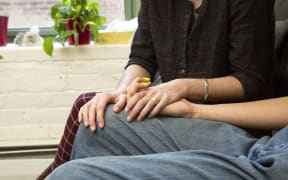 A couple holding hands on a couch.