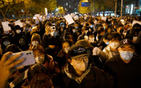 Protesters march along a street during a rally for the victims of a deadly fire as well as a protest against China's harsh Covid-19 restrictions in Beijing on 28 November, 2022.