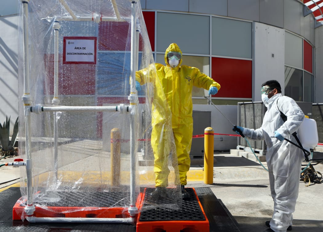 Sanitization of health workers wearing protective suits is demonstrated at a mobile hospital for people infected with COVID-19 in Ciudad Juarez, Mexico, on April 16, 2020.