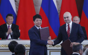 Chinese President Xi Jinping, left, and Russian President Vladimir Putin, right,  applaud as Russia and Huawei representatives shake hands.