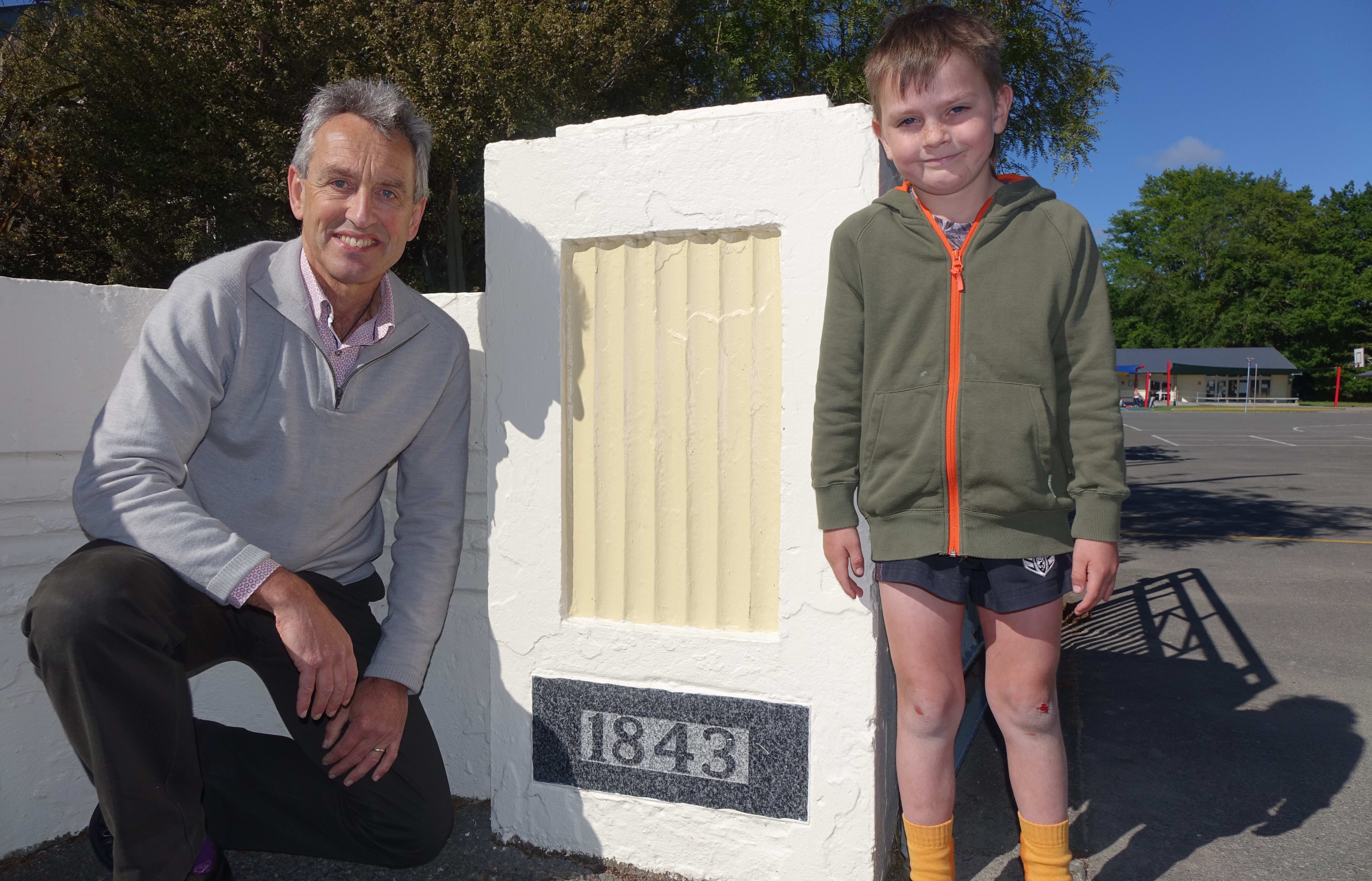 Principal Peter Verstappen with Kyro David Peter Baigent stand beside the sign which marks the opening year of Wakefield School.