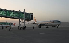 Members of ground staff stand on the tarmac as a Qatar Airways aircraft taxis before taking off from the airport in Kabul on 9 September 2021.