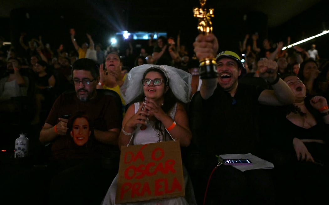 People in Sao Paulo, Brazil celebrate the victory of the Brazilian film Ainda Estou Aqui 'I'm Still Here' in the best international film category during the transmission of the 97st Academy Awards at a movie theater in Sao Paulo, Brazil on March 2, 2025. Brazil won its first-ever Oscar on Sunday in Hollywood with “I'm Still Here,” a drama about the disappearance of former congressman Rubens Paiva during the military dictatorship, which triumphed as best international film. (Photo by NELSON ALMEIDA / AFP)