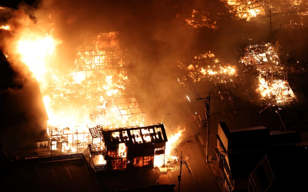 This aerial photo shows buildings burning in the city of Wajima, Ishikawa prefecture on 1 January, 2024, after a major earthquake struck Japan's Noto region. Tsunami waves over a metre high hit central Japan on after a series of powerful earthquakes that damaged homes, closed highways and prompted authorities to urge people to run to higher ground.