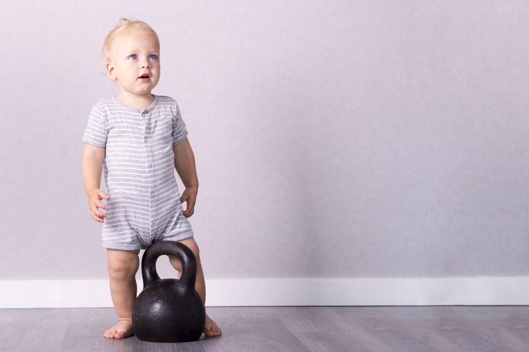 82735146 - adorable toddler in retro style sport suit going to lift a kettlebell