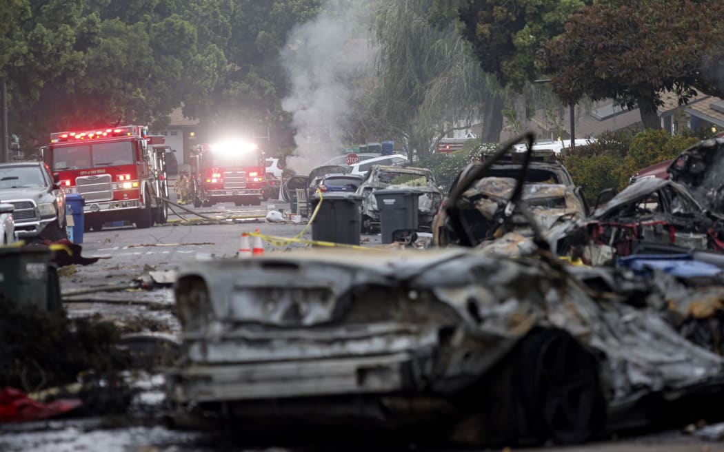 Firefighters work the site where a small plane crashed into a San Diego, California, residential street on May 22, 2025. The Federal Aviation Authority said a Cessna 550 crashed at around 3:45 am local time. The neighborhood is close to the Montgomery-Gibbs Executive Airport. The crash left a "gigantic debris field" and damaged some 15 homes and parked cars, ABC News quoted the San Diego assistant fire chief as saying. (Photo by Sandy Huffaker / AFP)