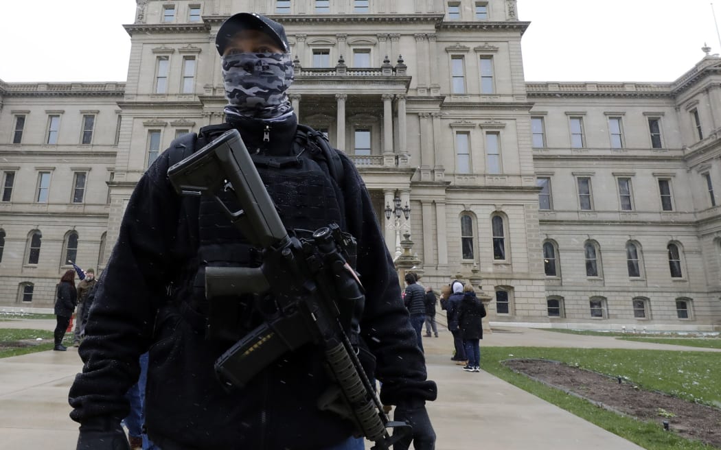 (FILES) In this file photo taken on April 15, 2020, an armed protester stands outside the Michigan State Capitol in Lansing, Michigan, during a demonstration against Michigan Governor Gretchen Whitmer's expanded the states stay-at-home order to contain the spread of the coronavirus. -