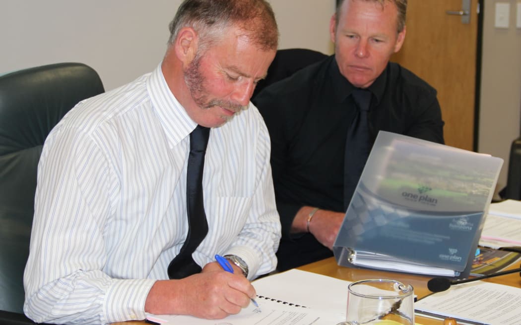 Regional council chairman Bruce Gordon signs the plan.