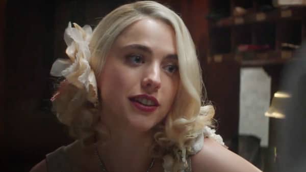 Margaret Qualley looks tenderly at something to the right of camera and has wavy platinum blonde hair and red lipstick.