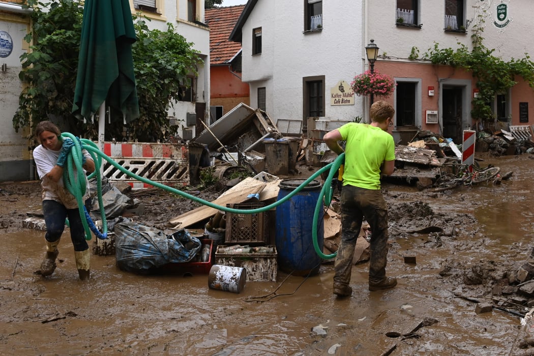 Local residents clean up a damaged street in Bad Neuenahr-Ahrweiler, western Germany, on July 16, 2021, after heavy rain hit.
