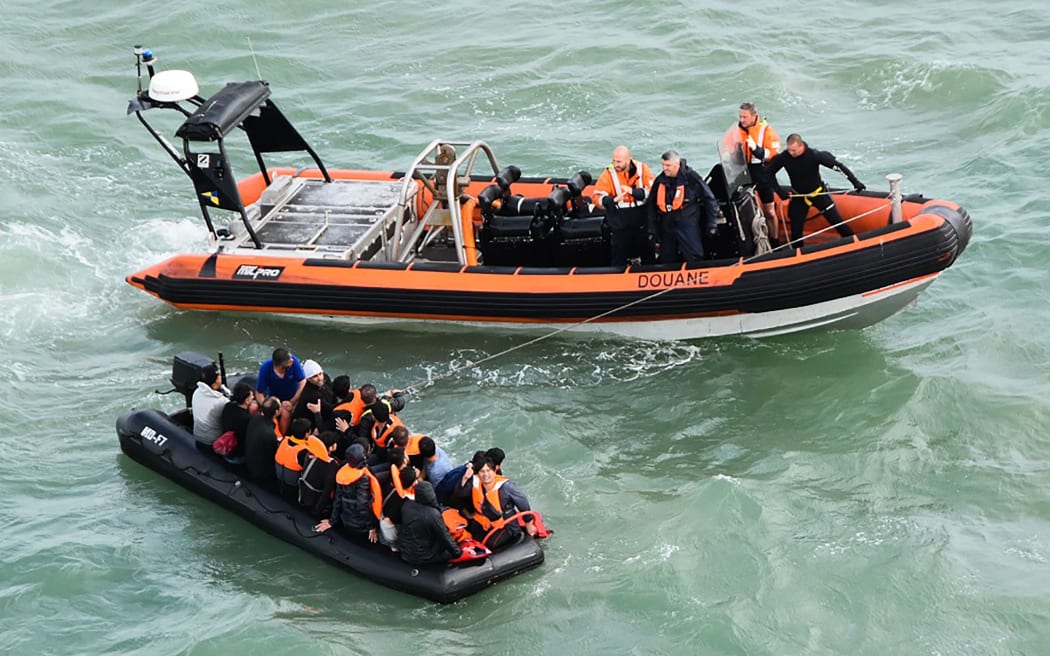 This handout photograph taken and released by the French Marine Nationale on August 5, 2019 shows migrants sitting in an inflatable dinghy rescued by French coast guards while trying to cross the Channel between France and Britain, off the coast of Graveline and the Cap Griz-Nez, on August 5, 2019.
