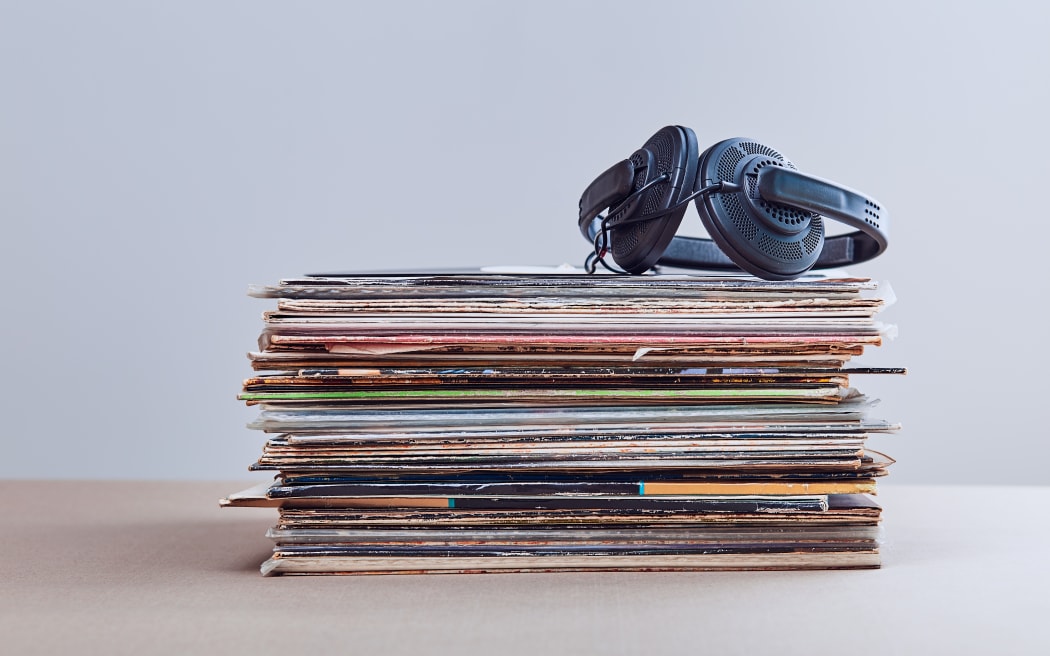 Stack of many black vinyl records, headphones put on the top of vinyls. Copy space for text. Candid people, real moments, authentic situations