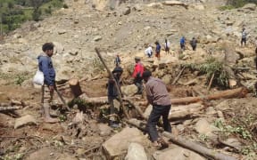 People dig through mud and rocks on 28 May, 2024, after a major landslide in Yambali village in Enga province, Papua New Guinea.