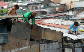 Residents along Manila Bay repair the roofs of their homes on May 10, 2015 in anticipation of Typhoon Noul as it approaches the northern Philippines.