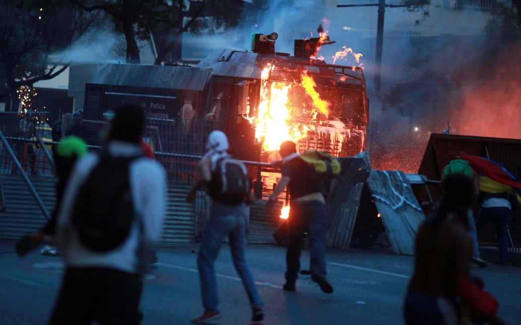 Demonstrators attack a water cannon during the protest in Caracas on Sunday.