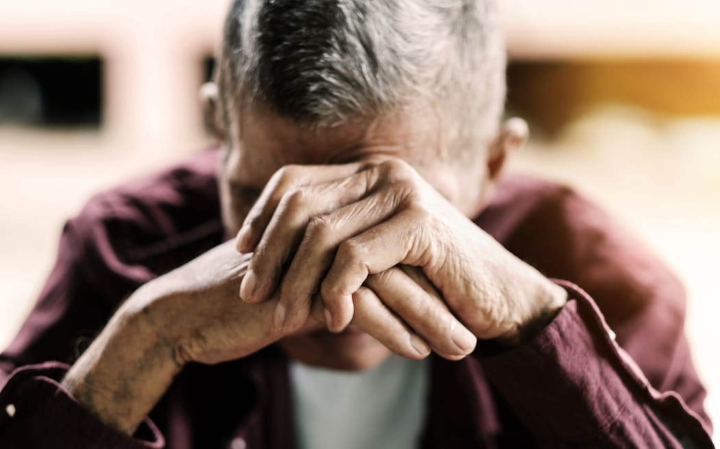 senior man covering his face with his hands.vintage tone