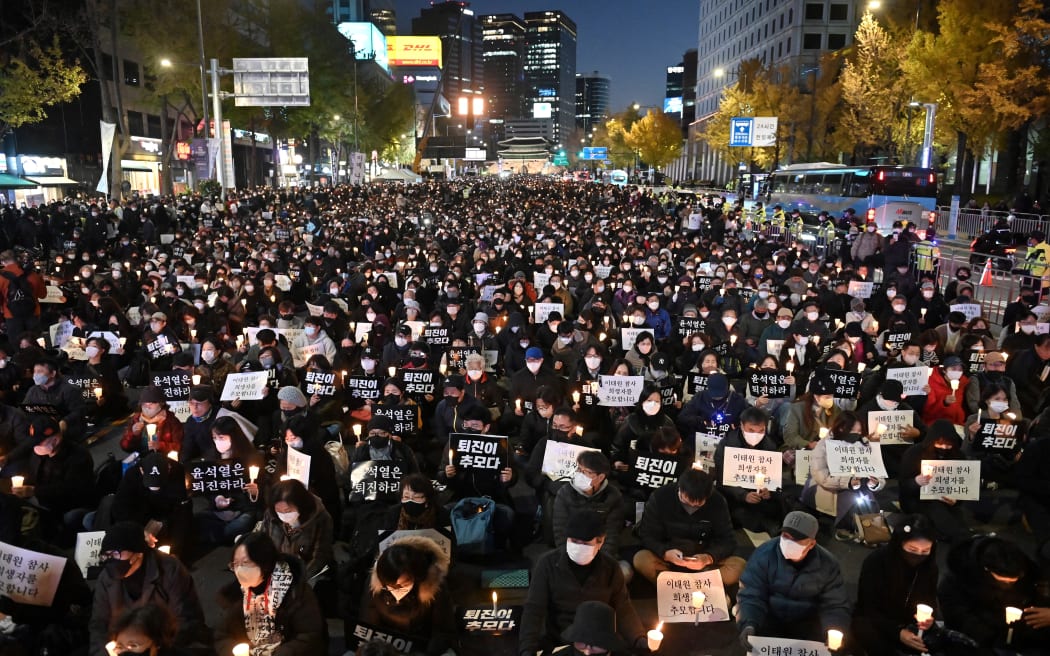 People take part in a candlelight vigil to commemorate the 156 people killed in the October 29 Halloween crowd crush, in Seoul on November 5, 2022. - Candlelight vigils and rallies were expected in South Korea on November 5 to commemorate the 156 people killed in a Halloween crowd crush, with public anger growing over one of the country's deadliest peacetime disasters. (Photo by Jung Yeon-je / AFP)