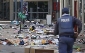 A looter runs from a member of the South African Police Services (SAPS) inside the Lotsoho Mall in Katlehong  township, East of Johannesburg, on July 12, 2021.