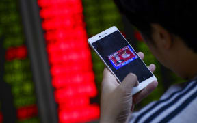 An investor looks at his smartphone showing results from the US presidential election, at a securities company in Beijing on November 9, 2016