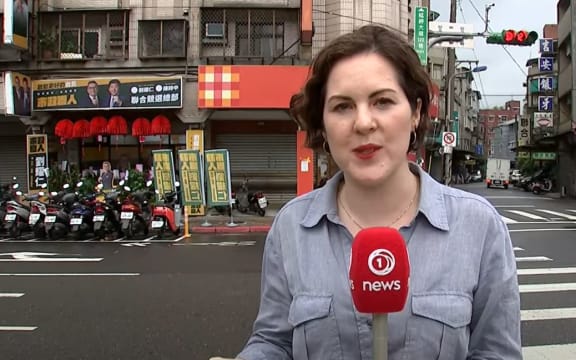 Cushla Norman in Taipei with ads for pro-Taiwan politicians over left shoulder -  and pro-China ones on the right.