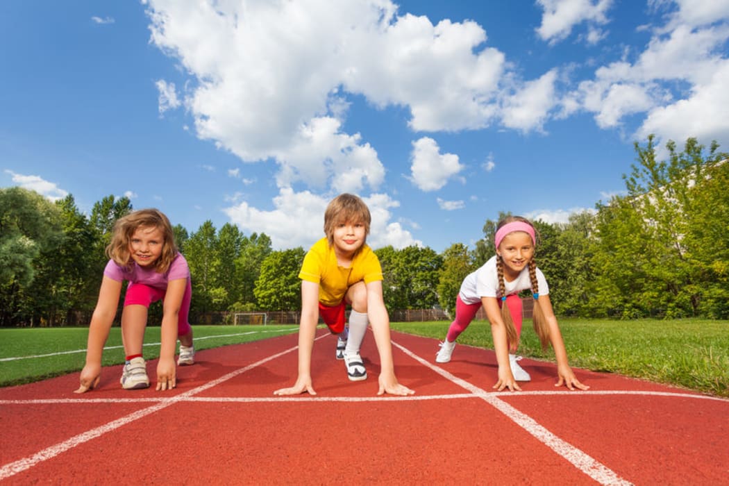 A photo of smiling children on bending knees ready to run a race