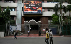 Pedestrians walk past a digital broadcast showing the Indian government’s military action code named Operation Sindoor, in Mumbai on May 7, 2025, as border tensions surge. India and Pakistan exchanged heavy artillery along their contested frontier on May 7, after New Delhi launched deadly missile strikes on its arch-rival in the worst violence between the nuclear-armed neighbours in two decades. India conducted several civil defence drills on May 7, while schools in Pakistan's Punjab and Kashmir were closed, local government officials said. (Photo by Indranil Mukherjee / AFP)