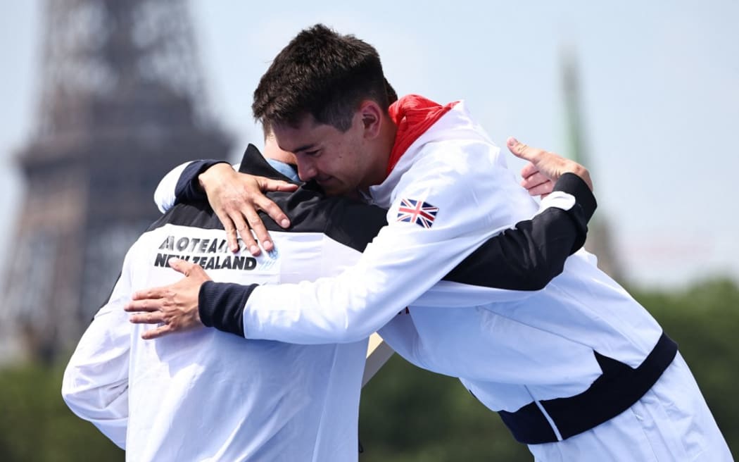 Gold medallist Britain's Alex Yee (R) hugs silver medallist New Zealand's Hayden Wilde during the victory ceremony for the men's individual triathlon at the Paris 2024 Olympic Games in central Paris on July 31, 2024. (Photo by Anne-Christine POUJOULAT / AFP)