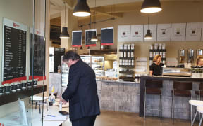 A customer signing in and sanitising their hands before ordering at Adoro Cafe in Napier.