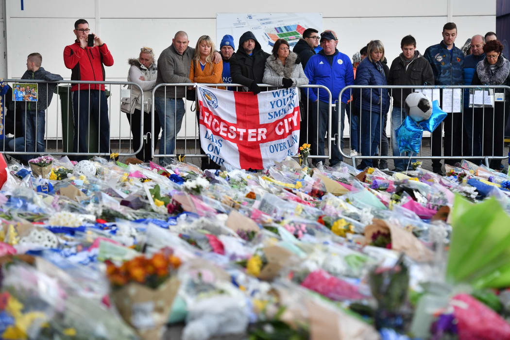 Supporters pause at the pile of floral tributes outside Leicester City Football Club's King Power Stadium.