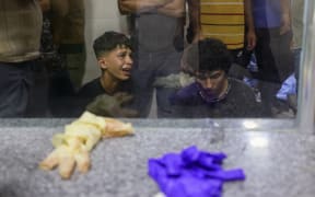 Palestinian youths mourn by the body of a relative killed in Israeli fire at a food aid distribution point set up by the privately-run Gaza Humanitarian Foundation (GHF) on the Salaheddin road, at Al-Awda hospital in the Nuseirat refugee camp in the central Gaza Strip on June 24, 2025.
