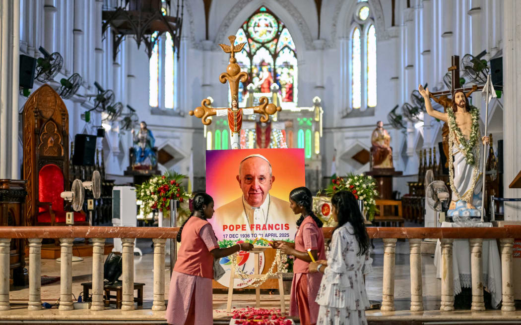 People pray in front of a portrait of Pope Francis at a Catholic church in Chennai on April 21, 2025,  following the news of his death. Pope Francis, an energetic reformer who inspired widespread devotion from Catholics but riled traditionalists, died on April 21, aged 88, just a day after greeting delighted worshippers after Easter Mass. (Photo by R. Satish BABU / AFP)