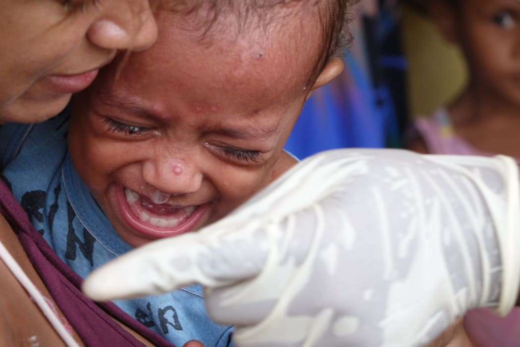 A child is immunised for measles in Vanuatu following Cyclone Pam.