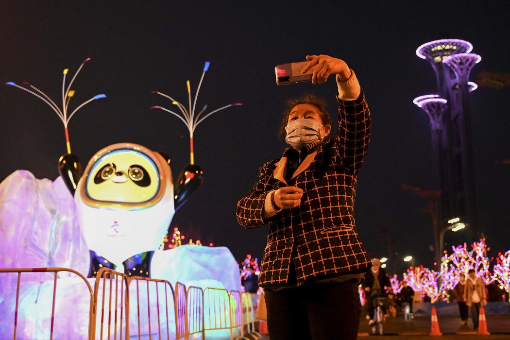 A woman takes a selfie in front of a display of Bing Dwen Dwen, the mascot of the 2022 Beijing Winter Olympics, at the Olympic Park in Beijing on January 18, 2022.