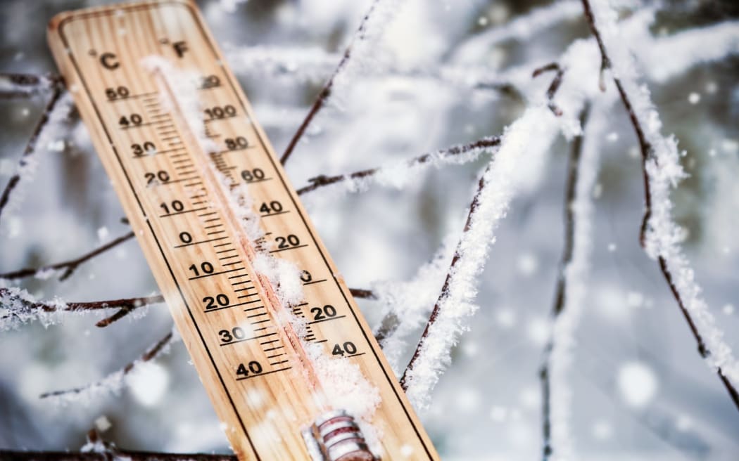 thermometer with plus temperature sticking out of the snow in the winter forest