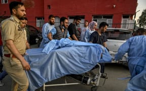 Paramedics and police personnel carry an injured tourist at a hospital in Anantnag, south of Srinagar, on April 22, 2025, following an attack. Gunmen in Indian-administered Kashmir opened fire on a group of tourists on April 22, with the chief minister saying the "inhuman" attack was one of the worst targeting civilians for years. At least five people were killed, a senior politician in the Himalayan region said. (Photo by Tauseef MUSTAFA / AFP)