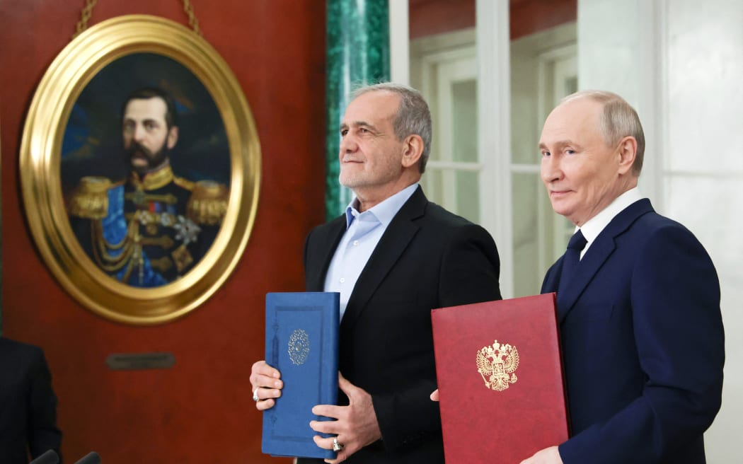 In this pool photograph distributed by the Russian state agency Sputnik, Russia's President Vladimir Putin and Iranian President Masoud Pezeshkian sign a strategic partnership treaty during a ceremony following their talks at the Kremlin in Moscow on January 17, 2025.