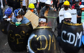 Protesters take cover behind homemade shields during a demonstration against the military coup in Yangon on February 28, 2021.