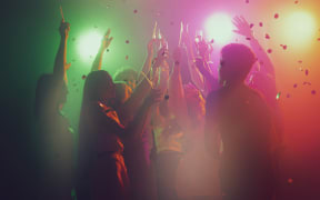 Group of young, active people at the night club, party dancing in neon lights.