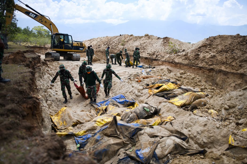 Indonesian soldiers bury quake victims in a mass grave in Poboya after an earthquake and tsunami hit the area on 28 September.