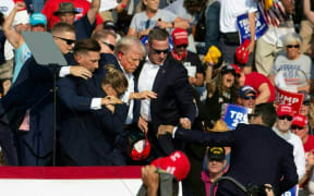 Republican candidate Donald Trump is seen with blood on his face surrounded by secret service agents as he is taken off the stage at a campaign event in Butler, Pennsylvania, 13 July, 2024.