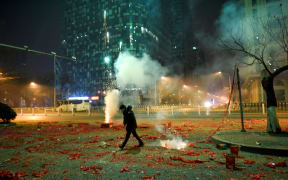 A man walks among firework papers in the streets of Beijing on 28 January, 2017, just after midnight marking the start of the Lunar New Year.