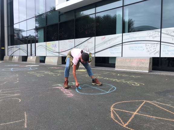 A protestor, Danielle Jones, makes her mark on the concrete outside BP’s Auckland office.
