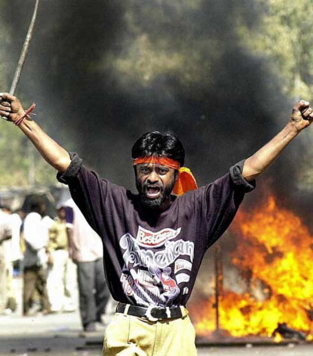 This picture taken 28 February 2002 shows an IndianBajranj Dal activist armed with a iron stick shouting slogans against muslims as they went burning muslim shops and attacked residences at Sahapur in Ahmedabad.