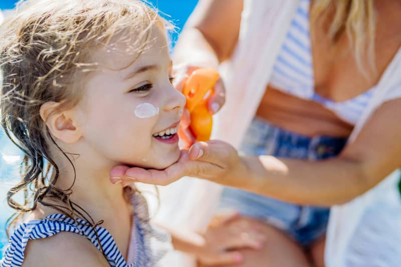 A child getting sunscreen applied to their face.