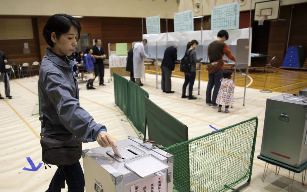 A woman casts her ballot for Japan's general election at a polling station in Tokyo.