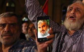 Men show photos of Hassan Nasrallah, Secretary-general of Hezbollah, as people demonstrate against Israel and the attack on Lebanon at Palestine square in Tehran on September 28, 2024. Israel conducted a wave of air strikes on the south of Lebanon's capital Beirut on September 27, 2024 that it said targeted Hezbollah's headquarters, warning of more to come as it told civilians to leave the densely populated neighbourhood. Israeli television networks reported that Hezbollah chief Hassan Nasrallah was the target of the strike, though a source close to the group said he was "fine". (Photo by ATTA KENARE / AFP)