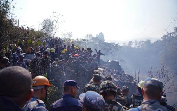 Rescuers gather at the site of a plane crash in Pokhara on January 15, 2023. - An aircraft with 72 people on board crashed in Nepal on January 15, Yeti Airlines and a local official said. (Photo by Yunish Gurung / AFP)