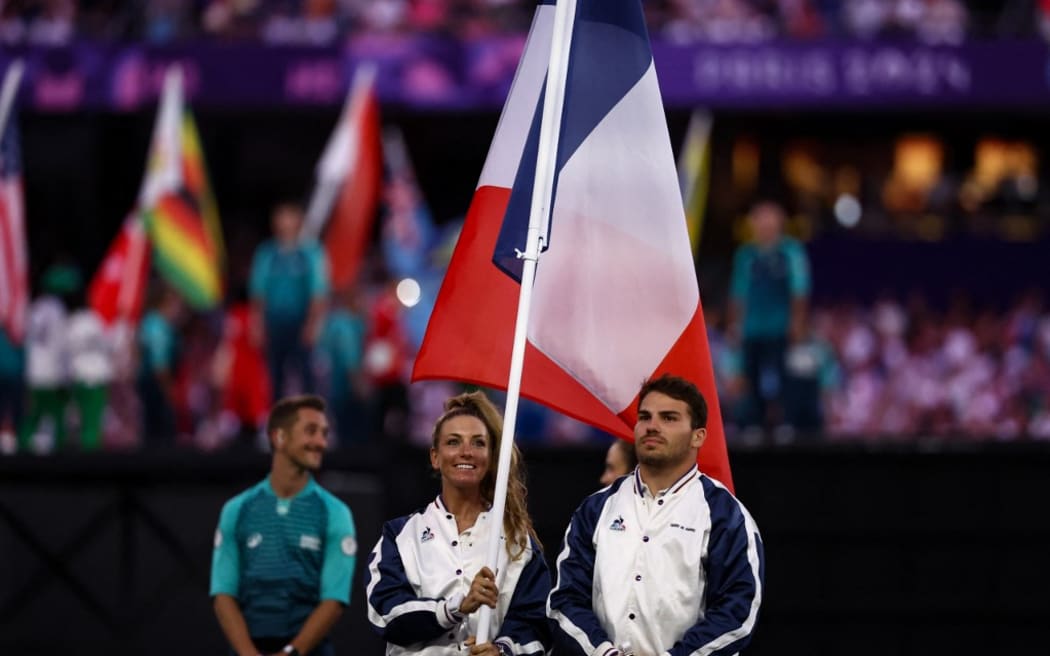 France's rugby player Antoine Dupont and France's cyclist Pauline Ferrand-Prevot wave the French national flag during the closing ceremony of the Paris 2024 Olympic Games at the Stade de France, in Saint-Denis, in the outskirts of Paris, on August 11, 2024. (Photo by Franck FIFE / AFP)